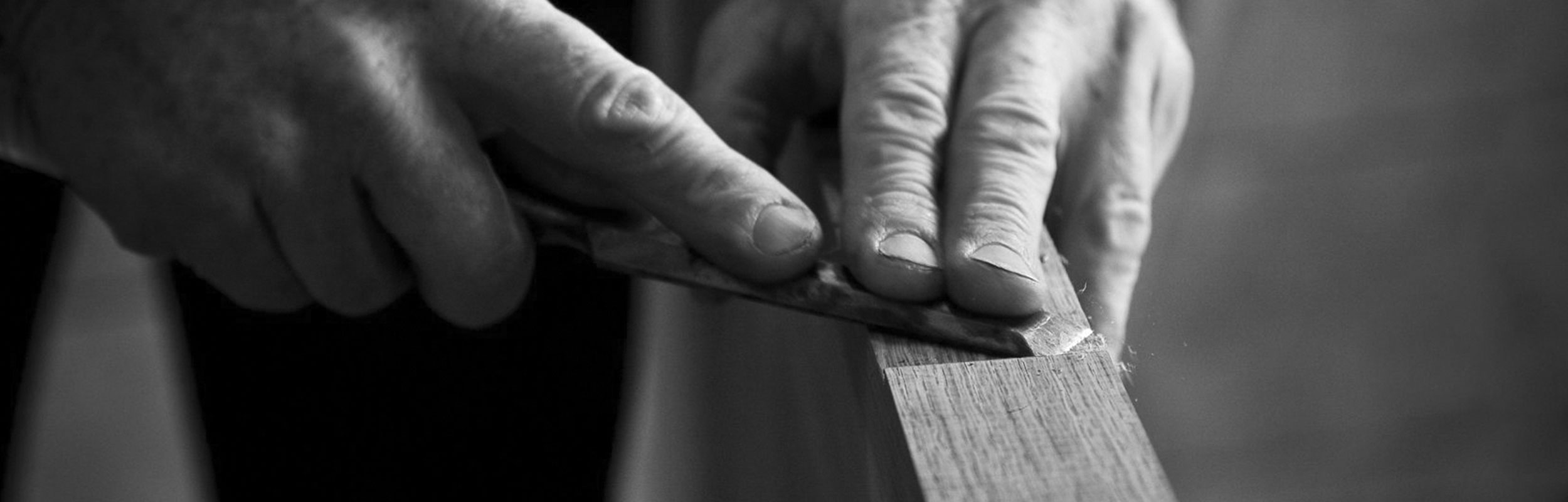 Le mani di un artigiano al lavoro su un pannello di legno